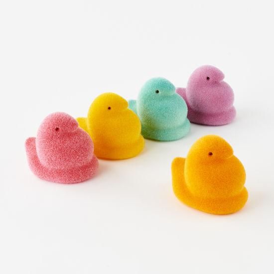 several small rubber ducks lined up in a row on a white surface with one yellow and one pink