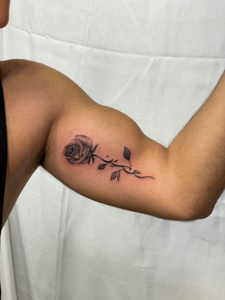 a man's arm with a rose and leaves tattoo on the left side of his arm