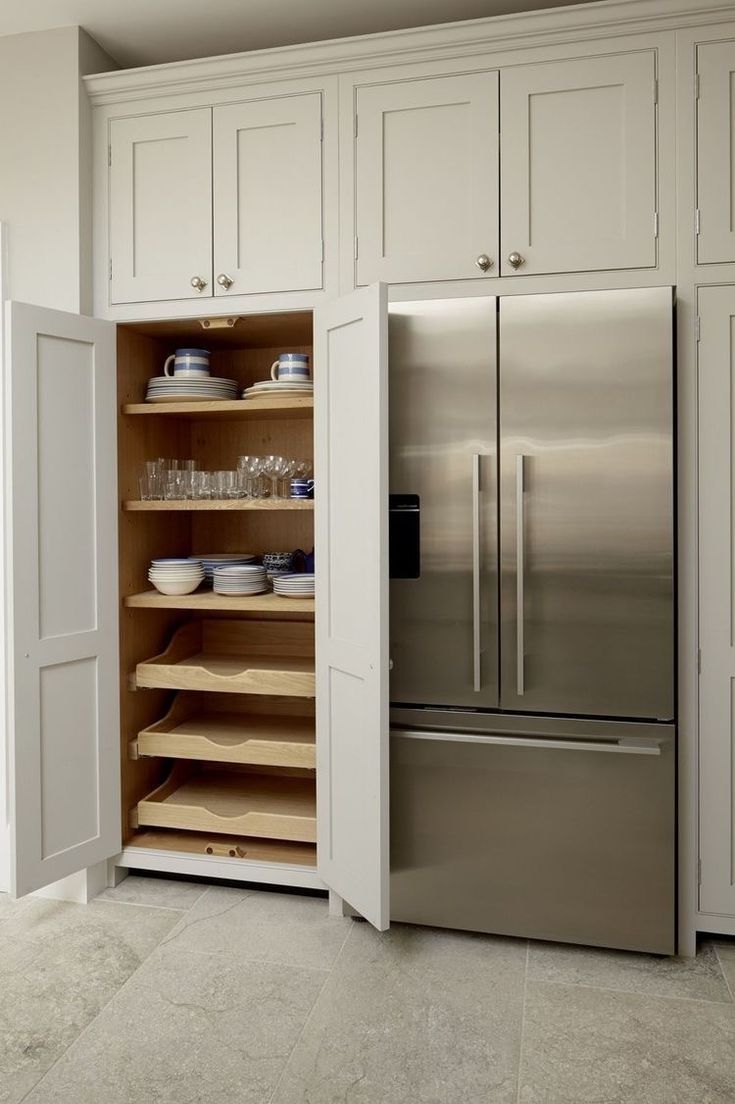 a kitchen with white cabinets and stainless steel refrigerator freezer combo in the center, open shelves on both sides