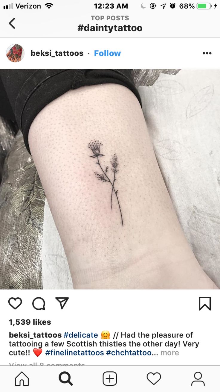 a small flower tattoo on the left side of the leg, with an inscription below it