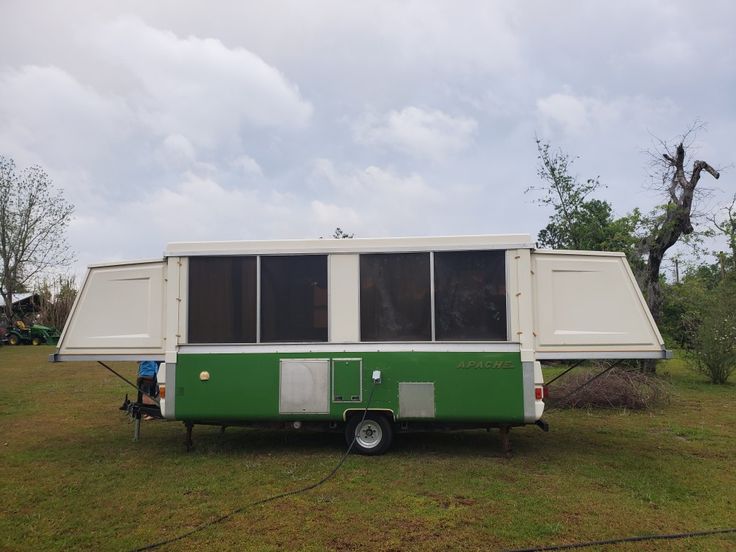 a green and white trailer parked on top of a grass covered field