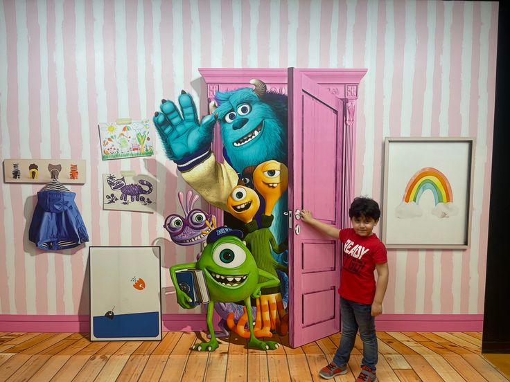 a young boy standing in front of a cartoon character painted on the side of a wall