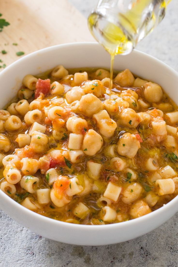 a white bowl filled with macaroni and cheese soup being poured into the bowl