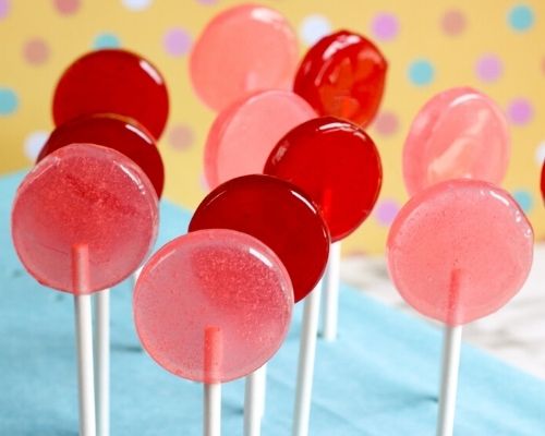 red and pink lollipops are sitting on a blue tablecloth with polka dots