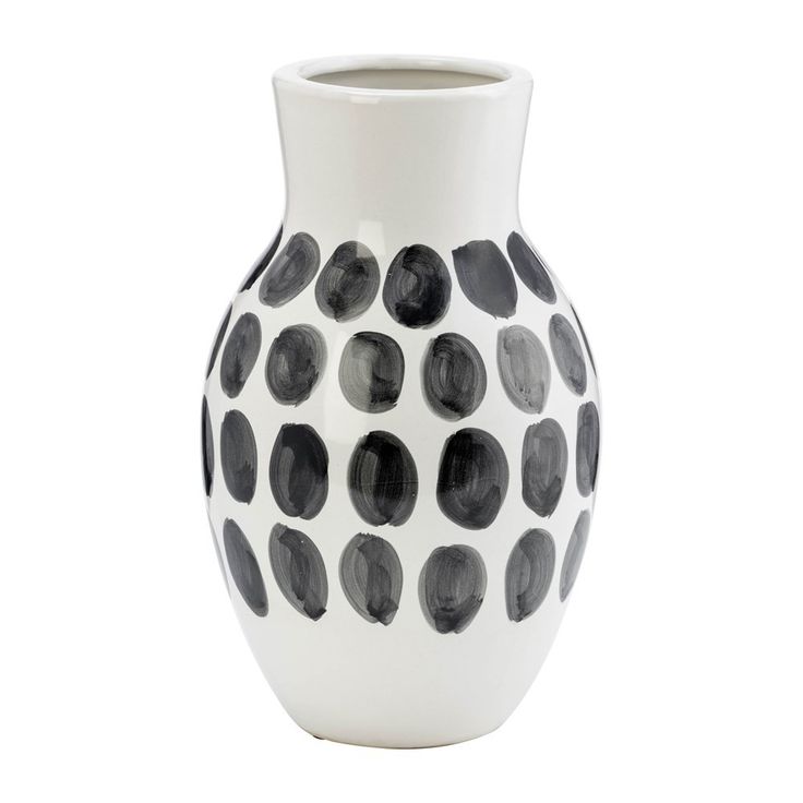 a black and white vase with dots on the bottom is sitting in front of a white background