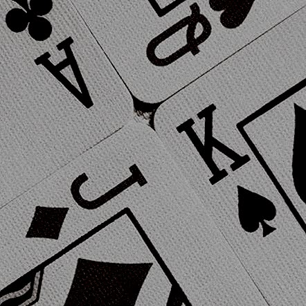 four playing cards with different symbols are shown in close up on the table top, including spades and clubs