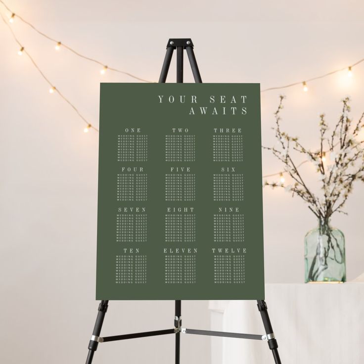 an easel with a seating chart on it in front of a string of lights