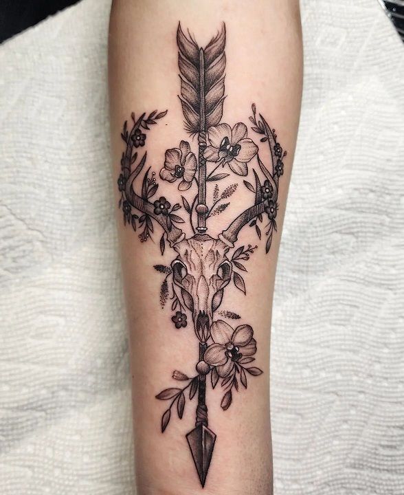 a black and white photo of a tattoo on the arm with flowers, feathers and an arrow