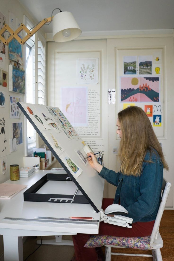 a woman sitting at a desk with an open laptop computer on it's side