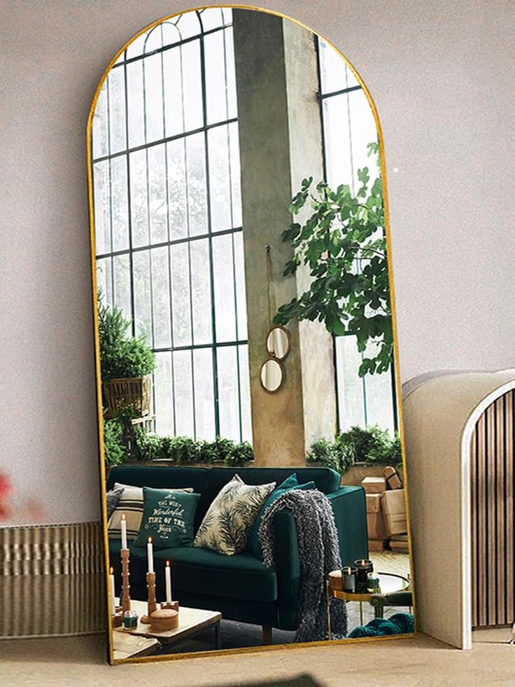 a living room with a green couch and large mirror in it's center area