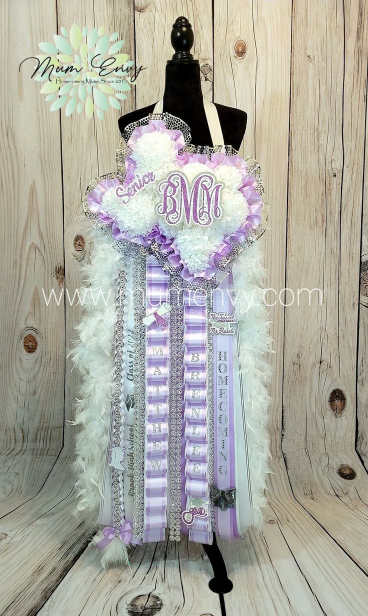 a mannequin with purple and white feathers on it's head is displayed in front of a wooden wall