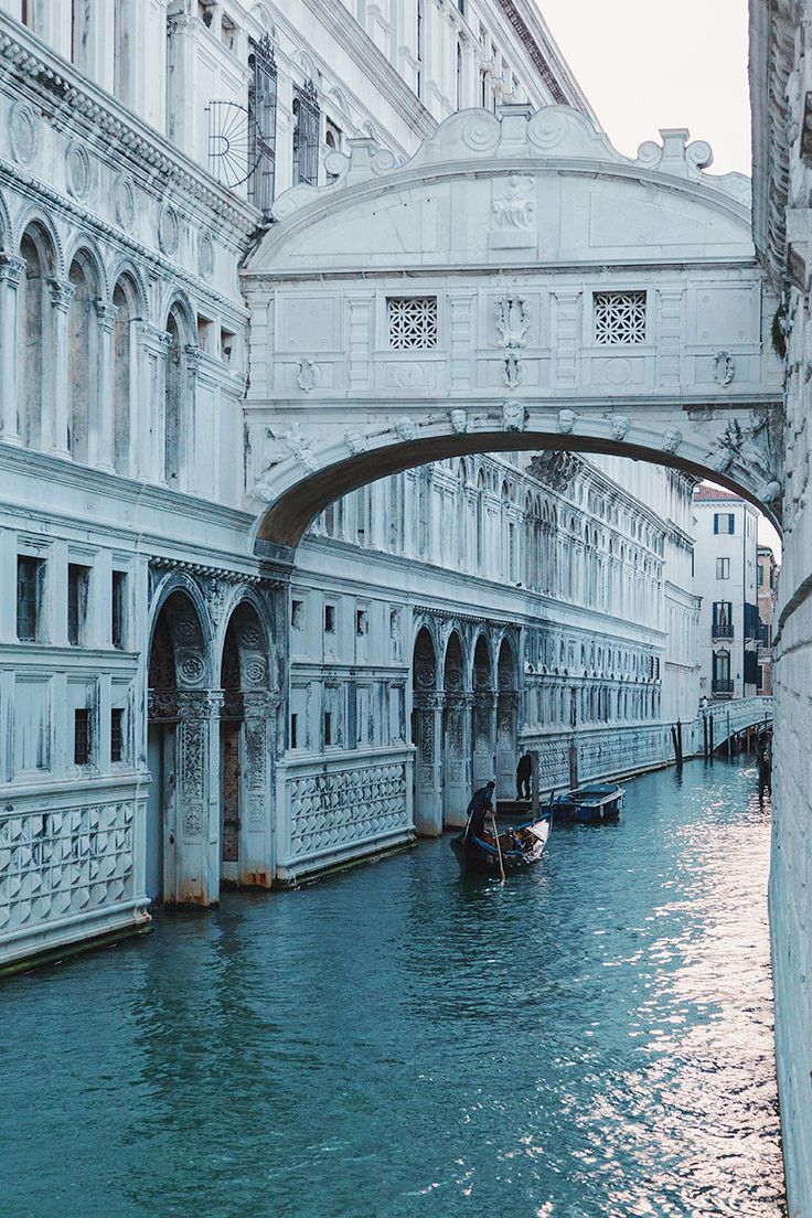 two gondolas are floating in the water under an arched bridge over a canal