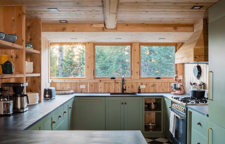 a kitchen with green cabinets and wooden walls