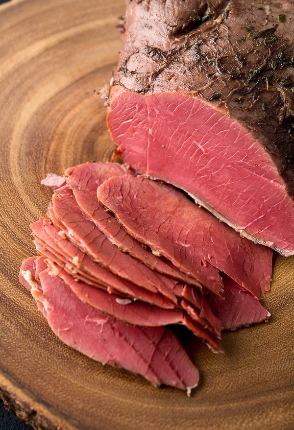 sliced meat sitting on top of a wooden cutting board