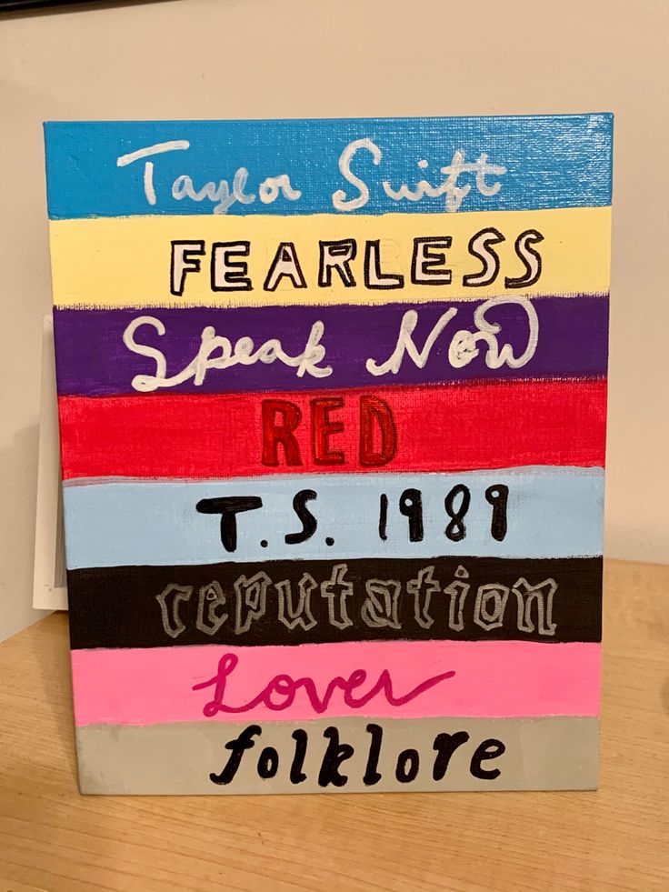 a wooden sign with different colored stripes on it that says fearless speak now red, ts199 revolution love folklore