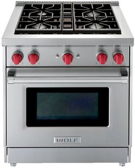 a silver stove top oven sitting on top of a white countertop with red knobs