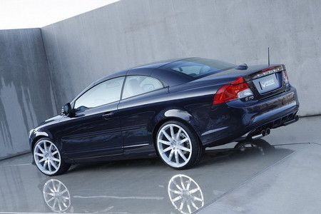 a blue car parked in a parking lot next to a cement wall with white rims