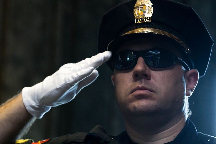 a police officer adjusts his cap on top of his head while wearing white gloves