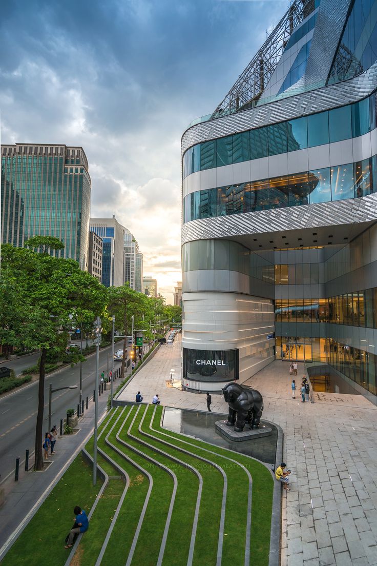 a large building that is next to a grassy area in the middle of a street