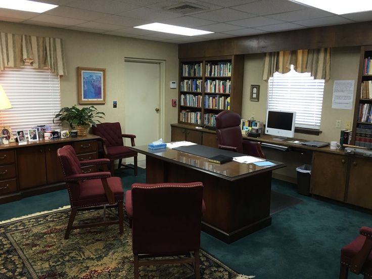 an office with chairs, desk and bookshelves