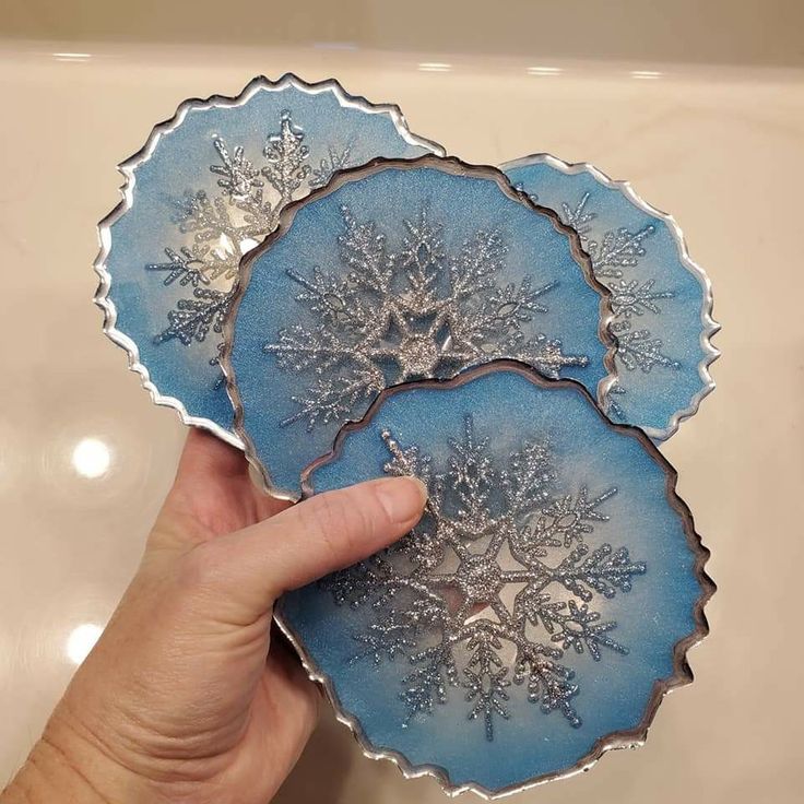 two blue plates with snowflakes on them are being held by a person's hand