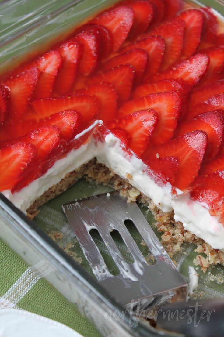 there is a cake with strawberries on top and a fork in the pan next to it