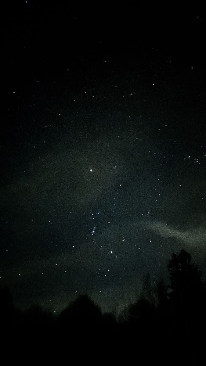 the night sky is filled with stars and clouds, as well as some dark trees