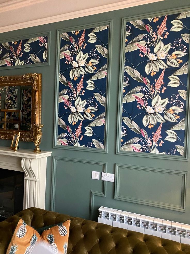 a living room with green walls and floral wallpaper on the fireplace mantels