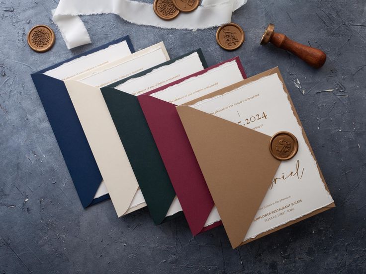 the wedding stationery is laid out on top of each other with wax and paper