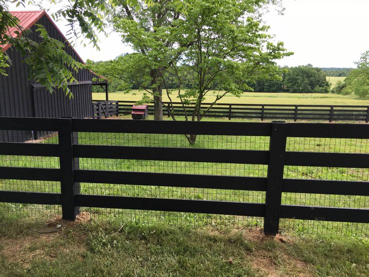 a black fence in front of a barn