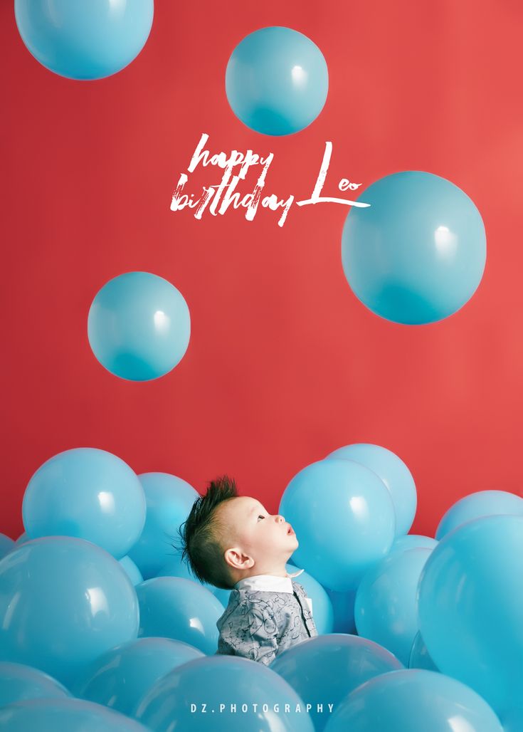 a baby is surrounded by blue balloons and the words happy birthday are written above it