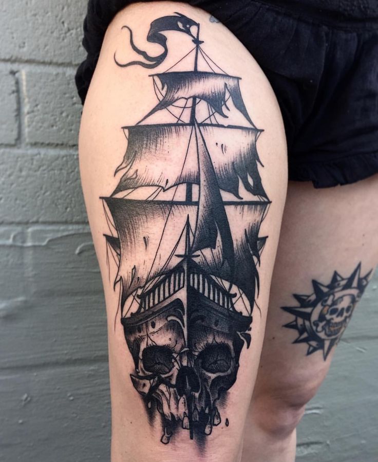 a woman's thigh with a black and white tattoo of a ship on it