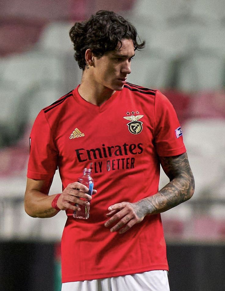 a soccer player holding a water bottle in his left hand and looking down at the ground