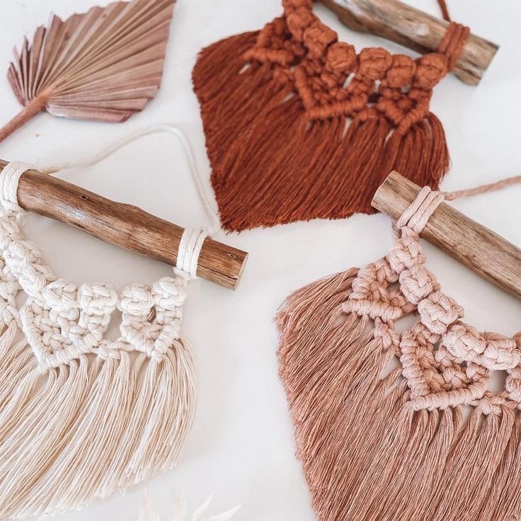 four different types of tassels on a white tablecloth with wood sticks and yarn