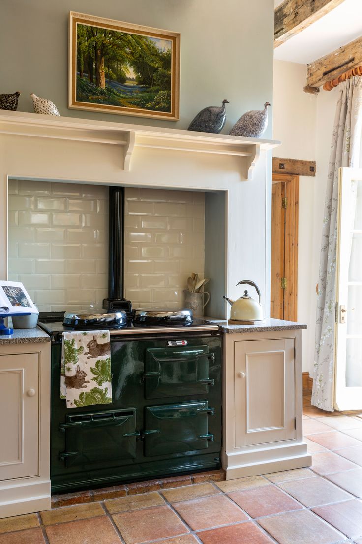 a green stove top oven sitting inside of a kitchen next to a painting on the wall