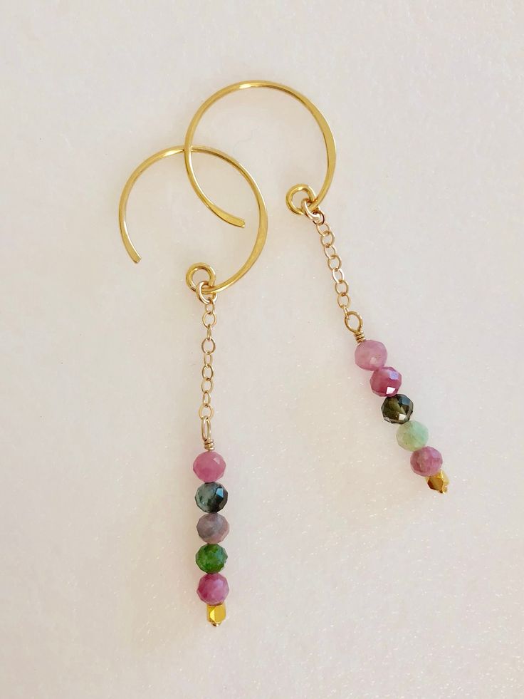 "Beautiful delicate faceted rainbow tourmaline dangles wire wrapped in gold on 24k gold vermeil ear wires. Natural 3.5-4 mm faceted rainbow tourmaline gemstones in shades of pink green and black. Gemstones are wire wrapped on delicate 24k gold fill chains which hang from petite 24k gold vermeil open circle ear wires. Total drop is 2 1/8\". Matching birthstone necklace also available in my shop. Please see last photo above. This listing is for earrings only. Also available in Sterling silver. Lov Handmade Gold Tourmaline Earrings, Yellow Gold Tourmaline Dangle Earrings, Yellow Gold Tourmaline Dangle Jewelry, Gold Tourmaline Drop Earrings, Gold Tourmaline Dangle Jewelry, Chip Jewelry, Black Gemstones, Rainbow Tourmaline, Red Garnet Earrings