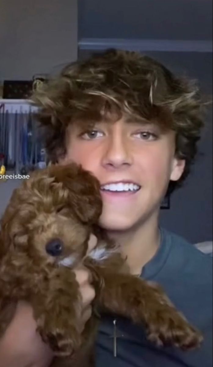 a young man holding a brown teddy bear