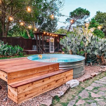 a hot tub in the middle of a garden with lights hanging from it's sides