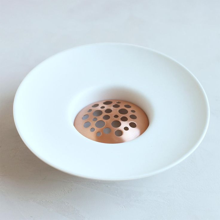 a white bowl with a metal strainer in the center on a table top,