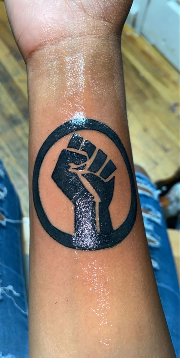 a person with a tattoo on their wrist holding up a fist in the middle of his arm