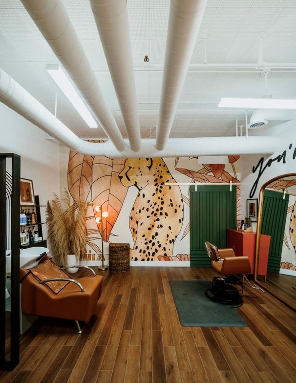 an office with wooden floors and walls decorated with paintings on the wall, two orange chairs in front of a yoga mat