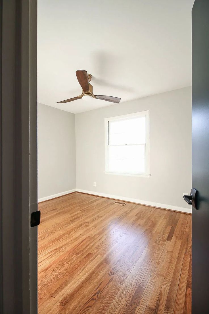 an empty room with hard wood floors and a ceiling fan