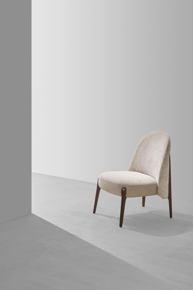 a white chair sitting on top of a cement floor next to a wall in an empty room