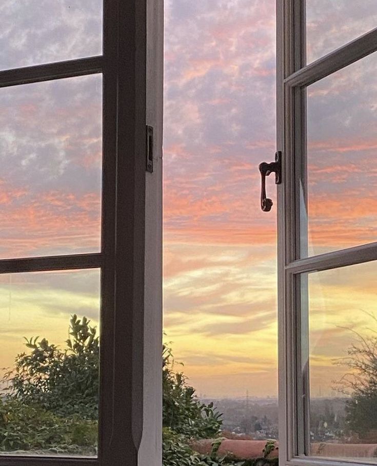 two open windows with the sunset in the background and trees out side at one end