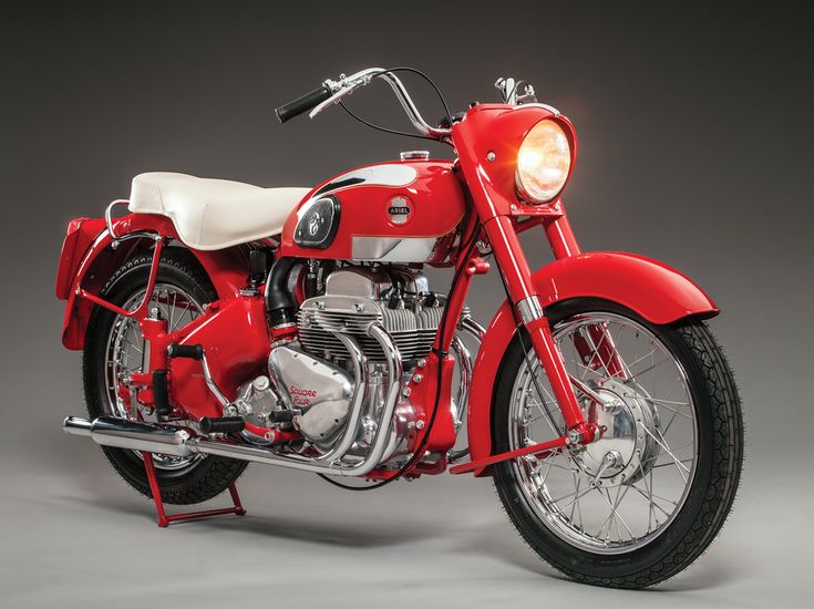 a red and white motorcycle parked on top of a gray floor next to a light