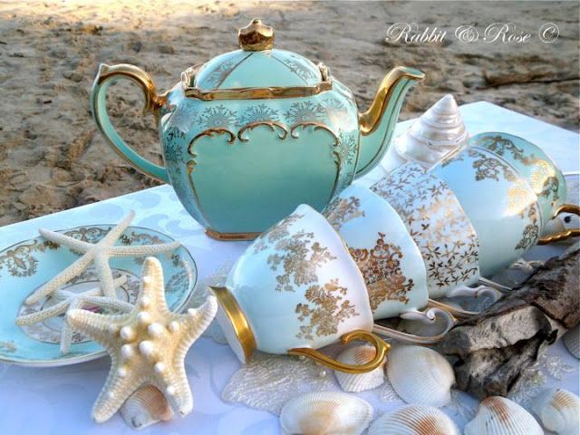 there is a tea set on the table with sea shells and starfish around it