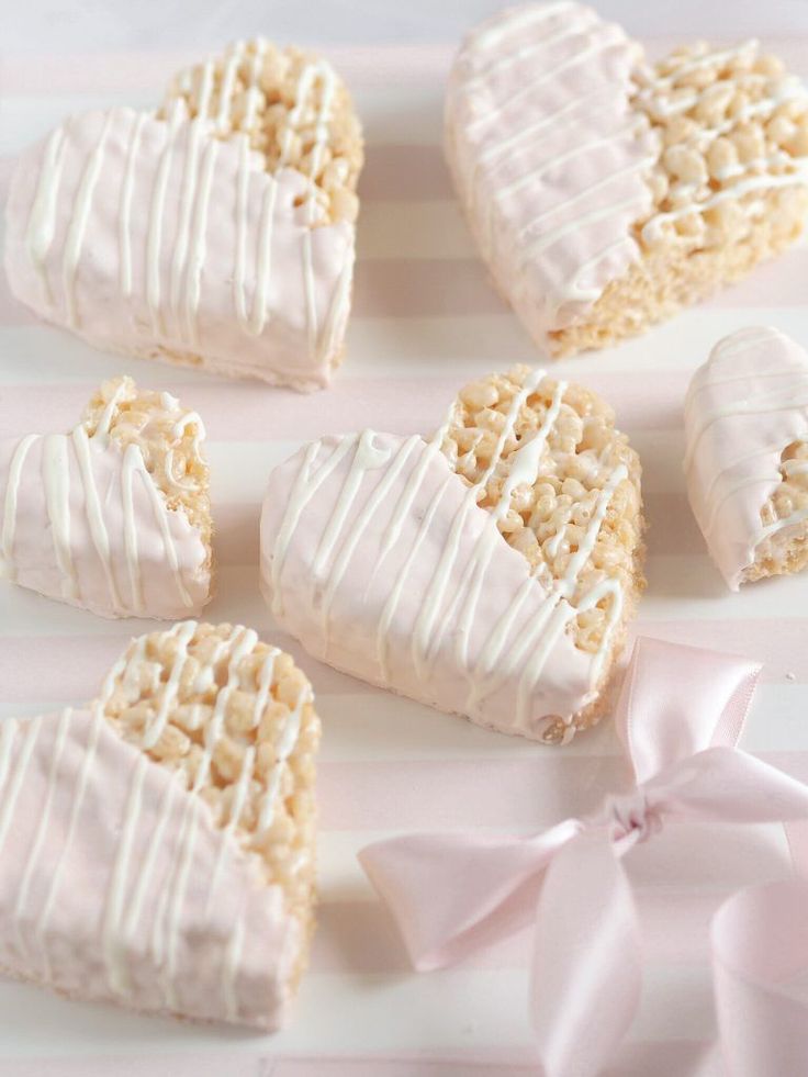 heart shaped cookies with white frosting on a pink and white striped plate next to a pink bow