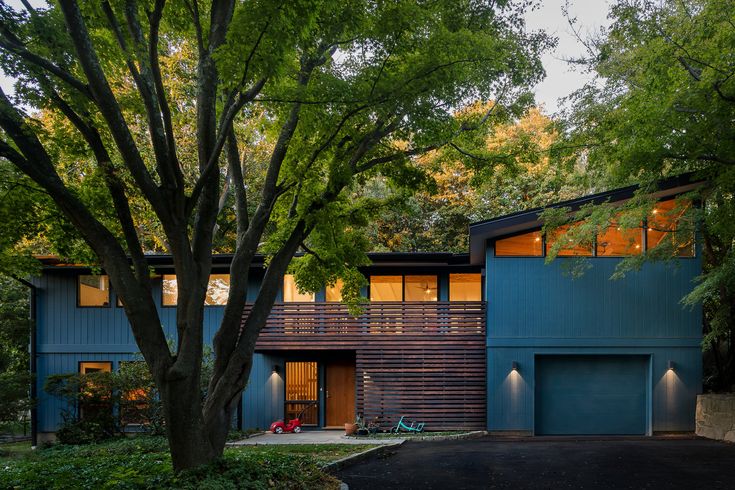 a blue house surrounded by trees in the evening