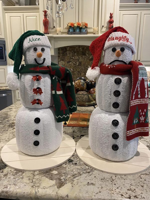 two snowmen with hats and scarfs on top of a kitchen counter in front of a fireplace