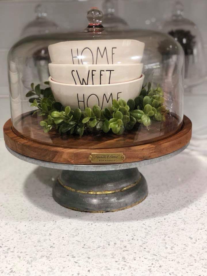 a bowl under a glass dome that says home sweet home on the bottom and green plants in it